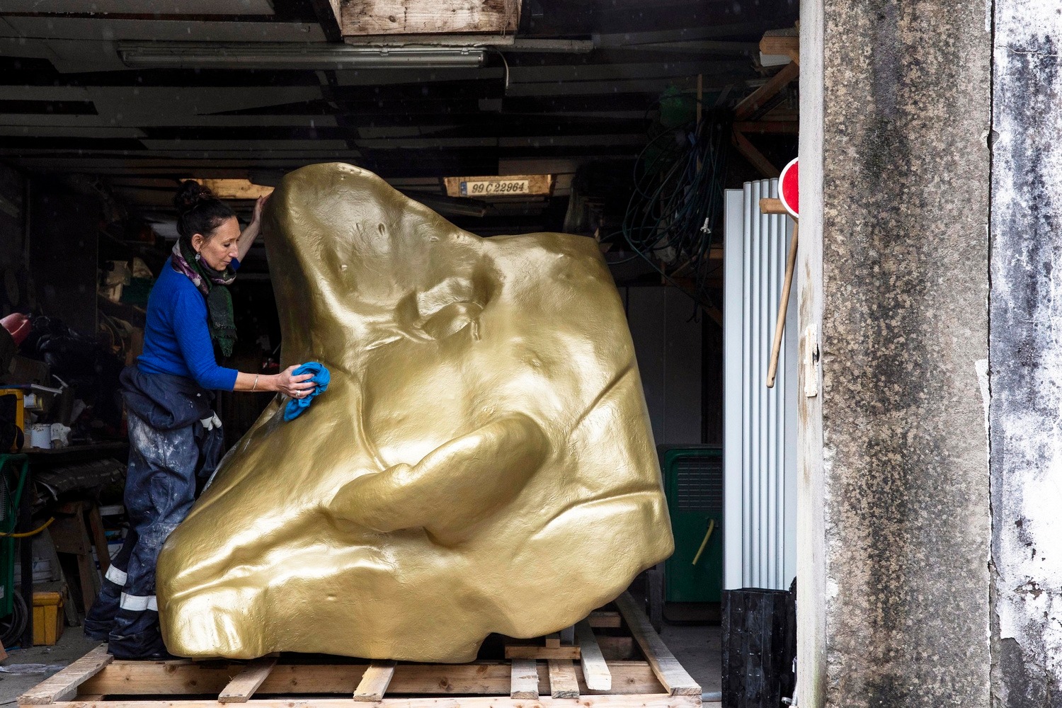 Artist pictured working on large gold-coloured art piece.