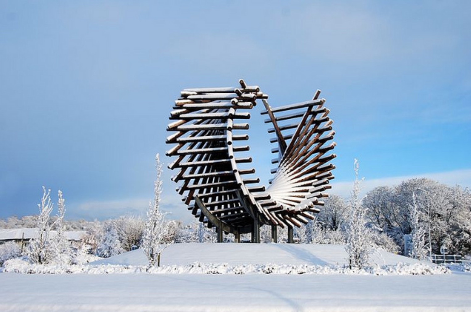 Wooden circular structure dusted with snow, with blue sky and snow in the foreground