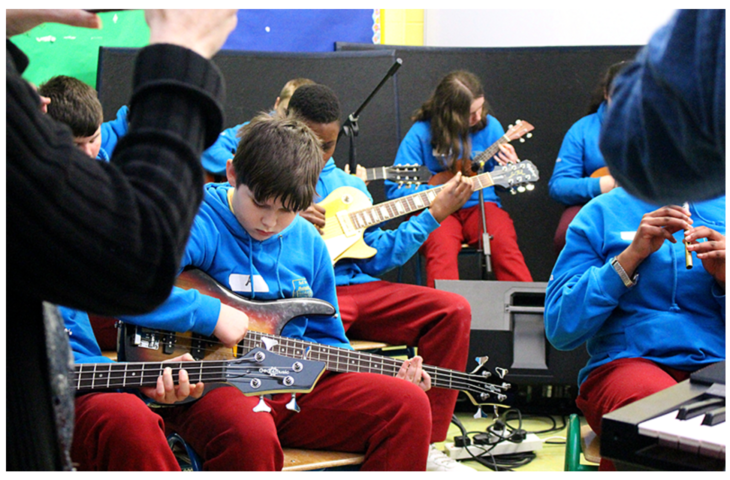 Students playing guitar in a group as a performance.
