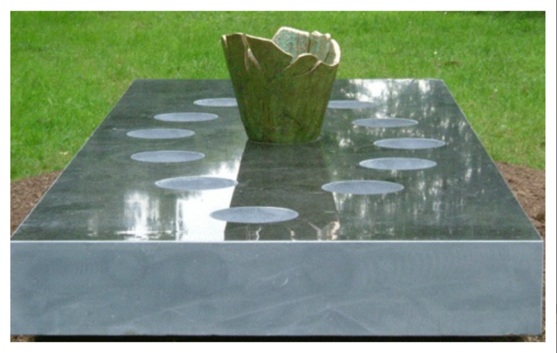 Stone plinth with carvings, green grass in background